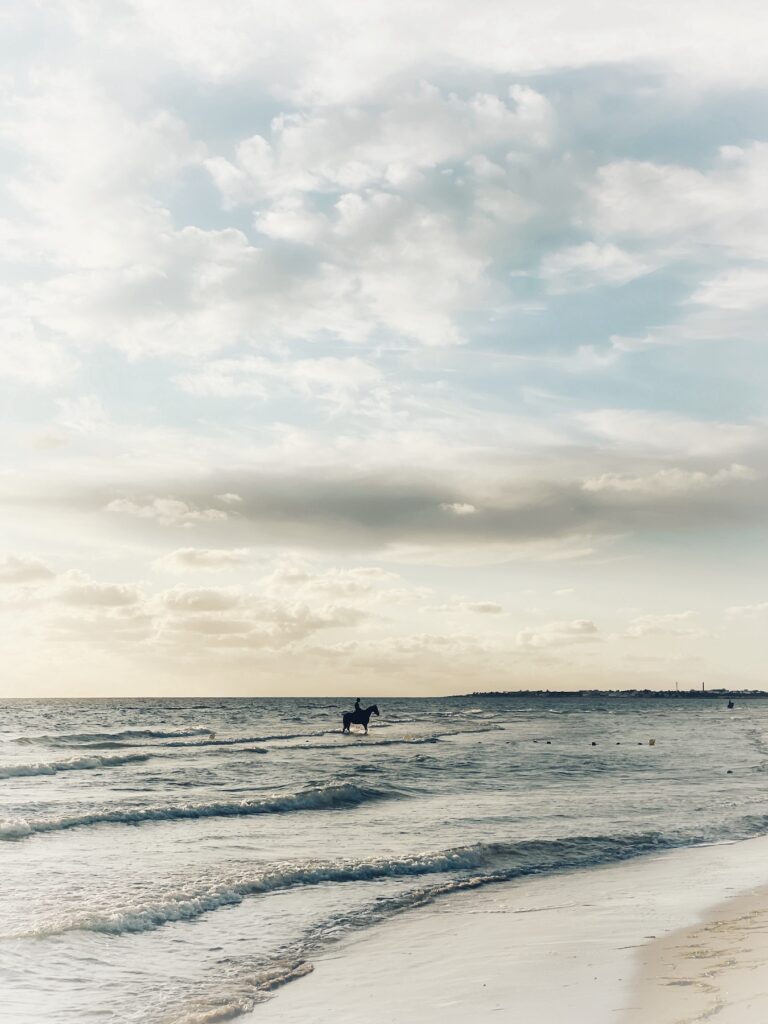 Reiter im seichten Wasser am Meeresstrand im weichen Morgenlicht.